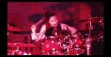 a woman is playing drums in a dark room with red lights
