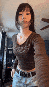 a woman is taking a selfie in a room with a ceiling fan in the background