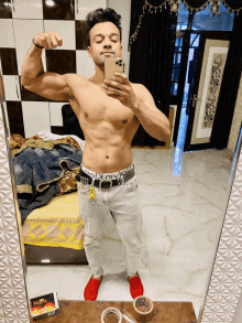 a shirtless man is taking a picture of himself in a mirror with a phone