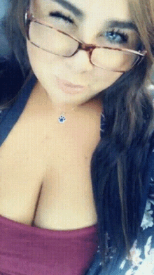 a woman wearing glasses and a necklace looks at the camera