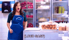 a woman in a blue apron is singing in front of a fridge that says loud gasp