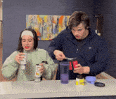 a man and a woman are sitting at a table holding cans of soda including one that says iced tea on it