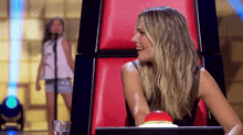 a woman is sitting in a chair with a red button on the back