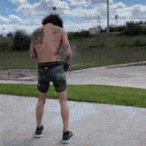 a man with a tattoo on his back is standing on a sidewalk