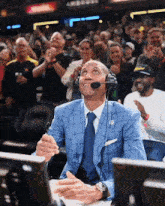 a man in a suit and tie wearing a microphone and headphones watches a basketball game