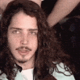 a close up of a man with long curly hair and a beard looking at the camera .