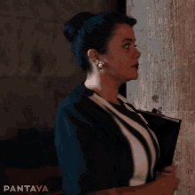 a woman in a black and white striped dress is standing in front of a wall with pantaya written on the bottom right