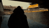 a man in a black coat is walking through a tunnel towards a stadium