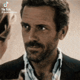 a man with a beard and a suit is looking at a woman .