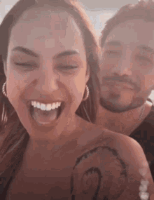 a man and a woman are laughing with their eyes closed .