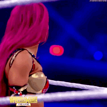 a woman with pink hair is standing in a ring with a sign that says wrestlemania theater .