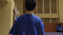 a man in a blue shirt stands in front of a sign that says ' ping pong '