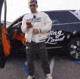 a man is standing in front of a car that says bling loud