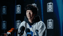 a man stands in front of a microphone with the word koi on the back