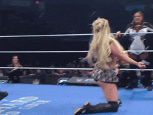 a woman is standing in a wrestling ring with a sign that says fmc on it