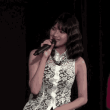 a woman singing into a microphone wearing a black and white lace top