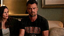 a man wearing a georgia t-shirt sits next to a woman