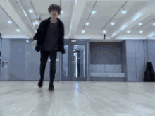 a man in a black jacket and black pants is standing on a wooden floor