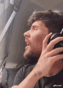 a man with a tattoo on his wrist is wearing headphones and singing into them .