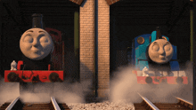 two thomas the tank engines are standing next to each other on the tracks