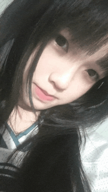 a girl with long black hair is taking a selfie with her eyes closed