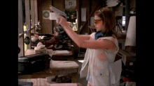 a woman is holding a gun in a room with a suitcase in the background .