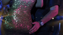 a woman in a sequined dress is dancing with a man behind her