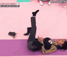 a woman is laying on a yoga mat with her legs crossed and the words whatsubs on the bottom left