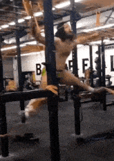 a man is doing pull ups in a gym with the letter b on the wall behind him