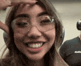 a woman wearing clear glasses and headphones smiles