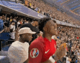 a man in a red nike shirt is standing in front of a crowd .