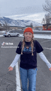 a girl wearing a harley davidson t-shirt is standing in a parking lot with her arms outstretched ..