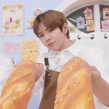 a boy holding a loaf of bread in front of a bakery shop poster