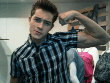 a man in a plaid shirt is flexing his arm