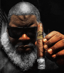 a man with a beard and sunglasses holds a cigar with the letter f on the label