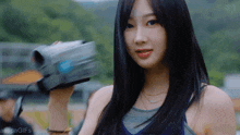 a young woman with long black hair is holding a video camera in her hand .