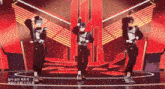 three anime characters are dancing on a stage with chinese writing on the bottom right