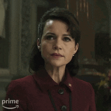 a woman is wearing a red dress and earrings and has an amazon prime logo on the bottom right