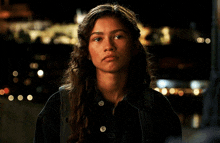 a woman with long hair is wearing a black jacket and backpack .