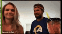 a man and a woman are having a video call on a computer screen . the man is wearing a rams shirt .
