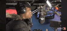 a man wearing headphones and a hat stands in front of a microphone that says tk radio