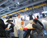 a group of people sitting at a table with a broken heart