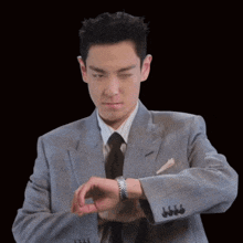 a man in a suit and tie is looking at his wrist watch