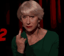 a woman in a green dress is giving the middle finger in front of the number 2