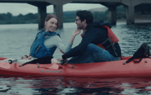 a man and a woman are in a red kayak that says perception on it