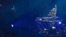 a man is singing into a microphone while standing on a stage in front of a keyboard .