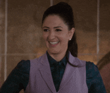 a woman in a purple vest and a green shirt smiles