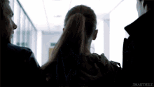 a woman in a ponytail is being held by a man in a hallway with the words smarthily visible in the corner