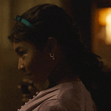 a woman wearing pearl earrings and a headband looks to the side