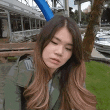 a woman with long hair is standing in front of a boat in a marina .
